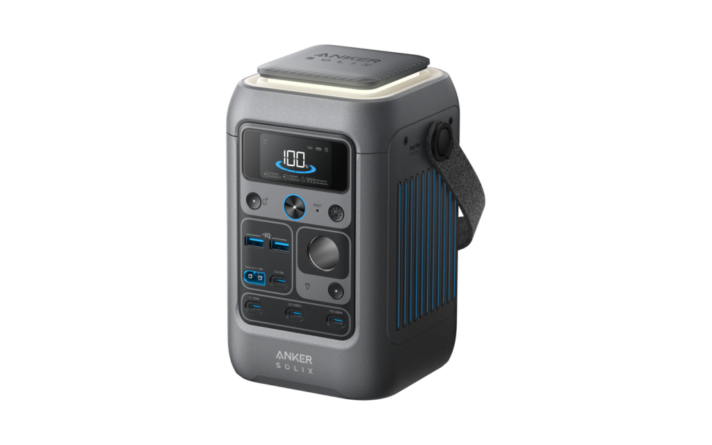 Three-quarter view of the Anker SOLIX C300 DC, a small gray power station with a display and port panel on the front, a fabric carry strap and a pop-out light on top.