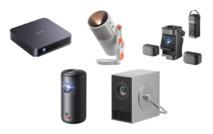 Five portable projectors on a white background: a flat dark gray Dangbei Atom, a white XGIMI MoGo 4 on its stand, a gray Nebula P1 with its two speakers detached, a black cylindrical Nebula Capsule 3, and a silver LG CineBeam Q with its handle.