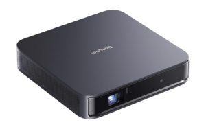 The Dangbei Atom laser projector, a flat dark gray square box with the Dangbei name on top and the lens at the front right corner.